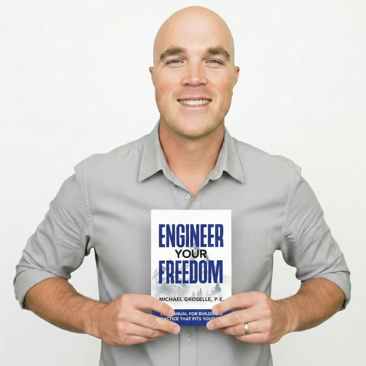 Michael Groselle smiling and holding a copy of Engineer Your Freedom.